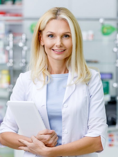 female-pharmacist-in-white-coat-holding-digital-tablet-and-smiling-at-camera-e1634020954198.jpg